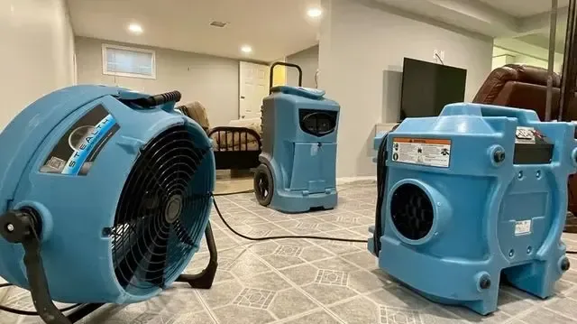 Air movers and a dehumidifier running in a room during a water damage dry-out
