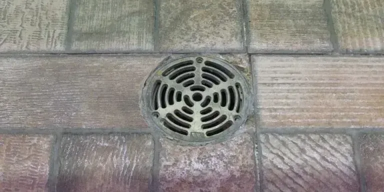 Metal grate over a basement floor drain, the first opening where a sewer backup shows