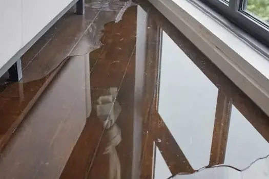 Rain water pooled on hardwood flooring under a window